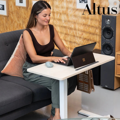 Casual work setting with a woman using a laptop on a minimalist white adjustable desk, showcasing the desk's usability in home office environments.