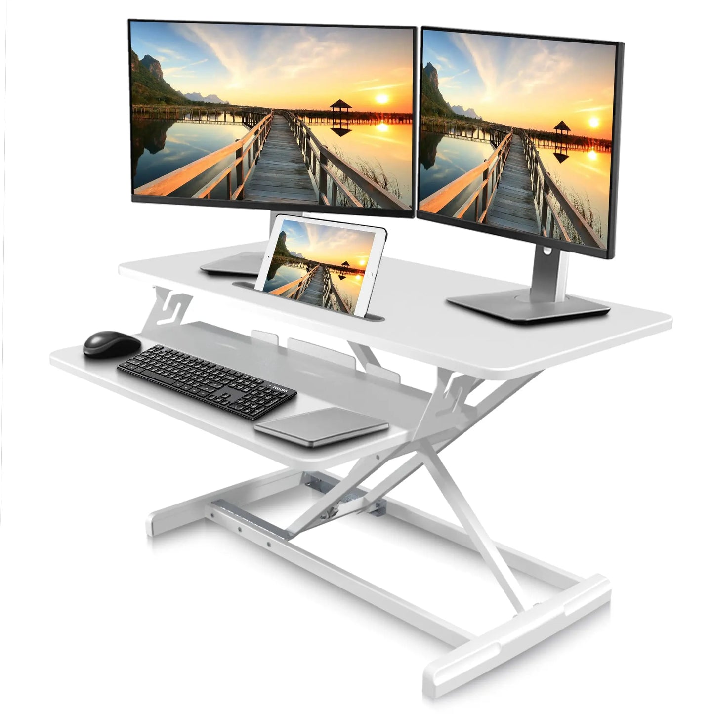 A modern white desk converter set up with two monitors displaying stunning sunset landscapes, a tablet, keyboard, and mouse on the lower shelf.