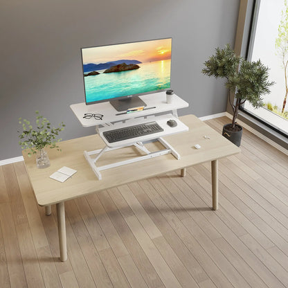 A serene office setup showing a white desk converter supporting a monitor and personal items, placed on a wooden desk near a window.