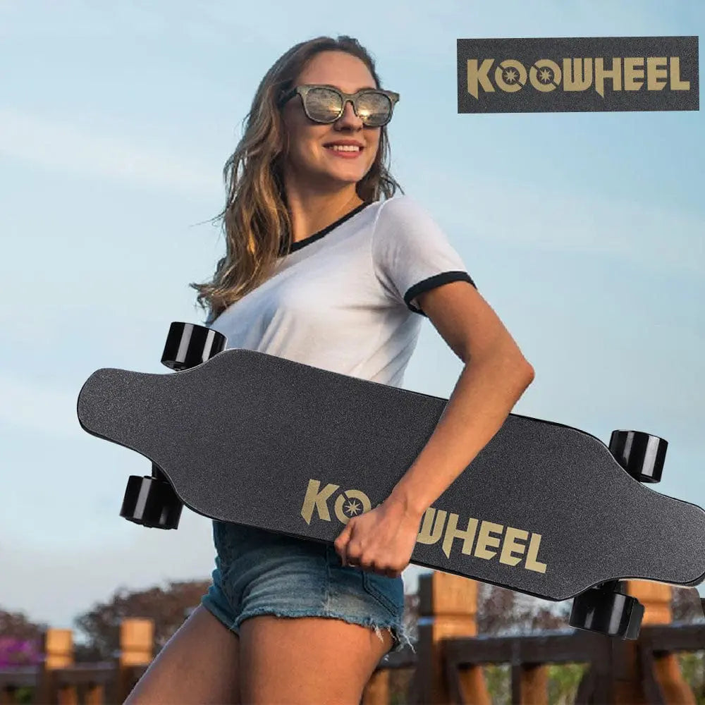 A woman holding a grey electric skateboard with "KOOWHEEL" logo outdoors, ready to ride, depicting a lifestyle image.