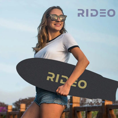 Image of a young woman holding the skateboard, showcasing its portability and style in an outdoor setting.