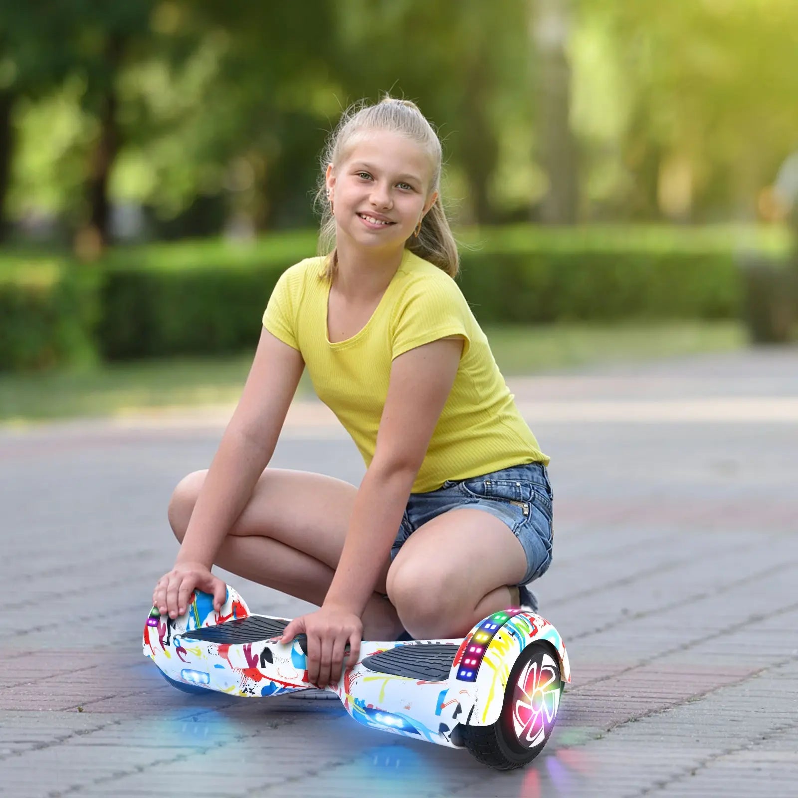 Photo of a young girl sitting next to her RIDEO Hoverboard in White Graffiti, highlighting the hoverboard’s appeal to children and teens