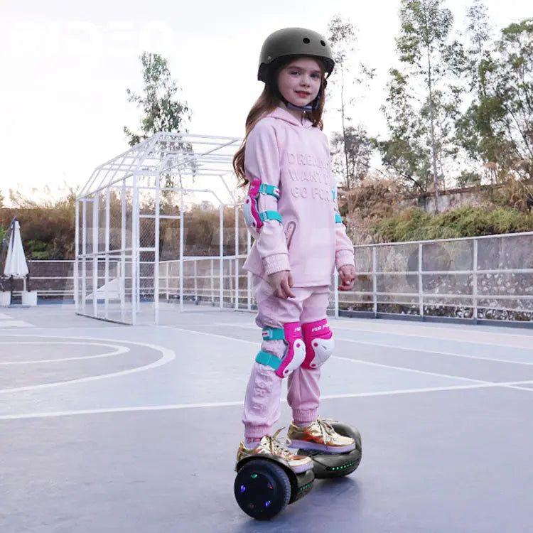 Young girl riding a RIDEO Q3c Self Balance Scooter in a pink outfit, equipped with helmet and safety pads, highlighting the hoverboard's stability and fun for kids.