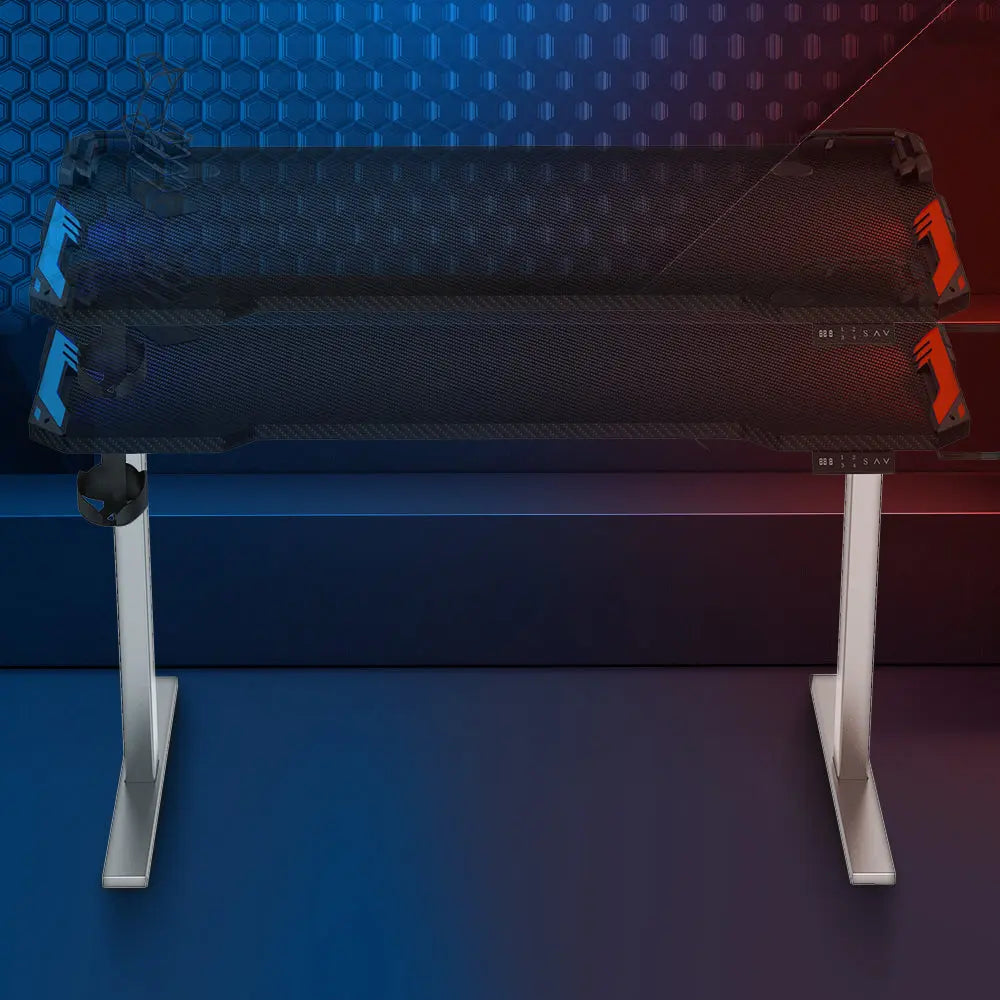 A close-up of the desk’s tabletop, displaying its textured surface and integrated features such as cable management and accessory holders, under a glowing blue and red lighting effect.